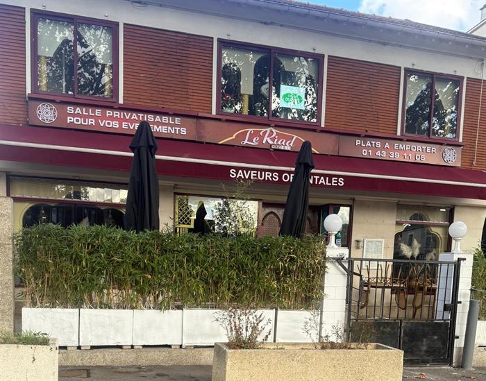 La façade du Riad : auvent bordeaux « Le Riad – Saveurs orientales », terrasse bordée de bambous