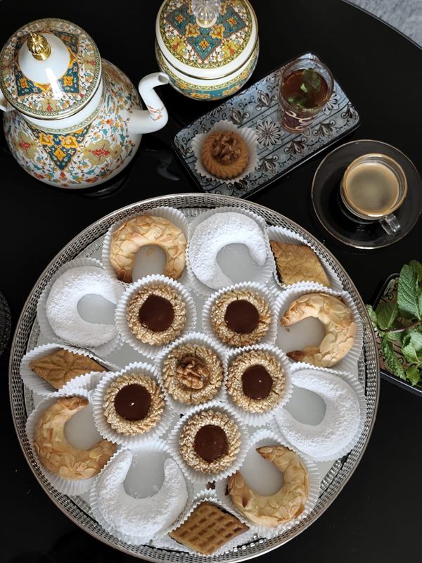 Plateau de pâtisseries orientales faites maison : cornes de gazelle aux amandes, croissants au sucre glace, sablés au sésame, servis avec le thé à la menthe