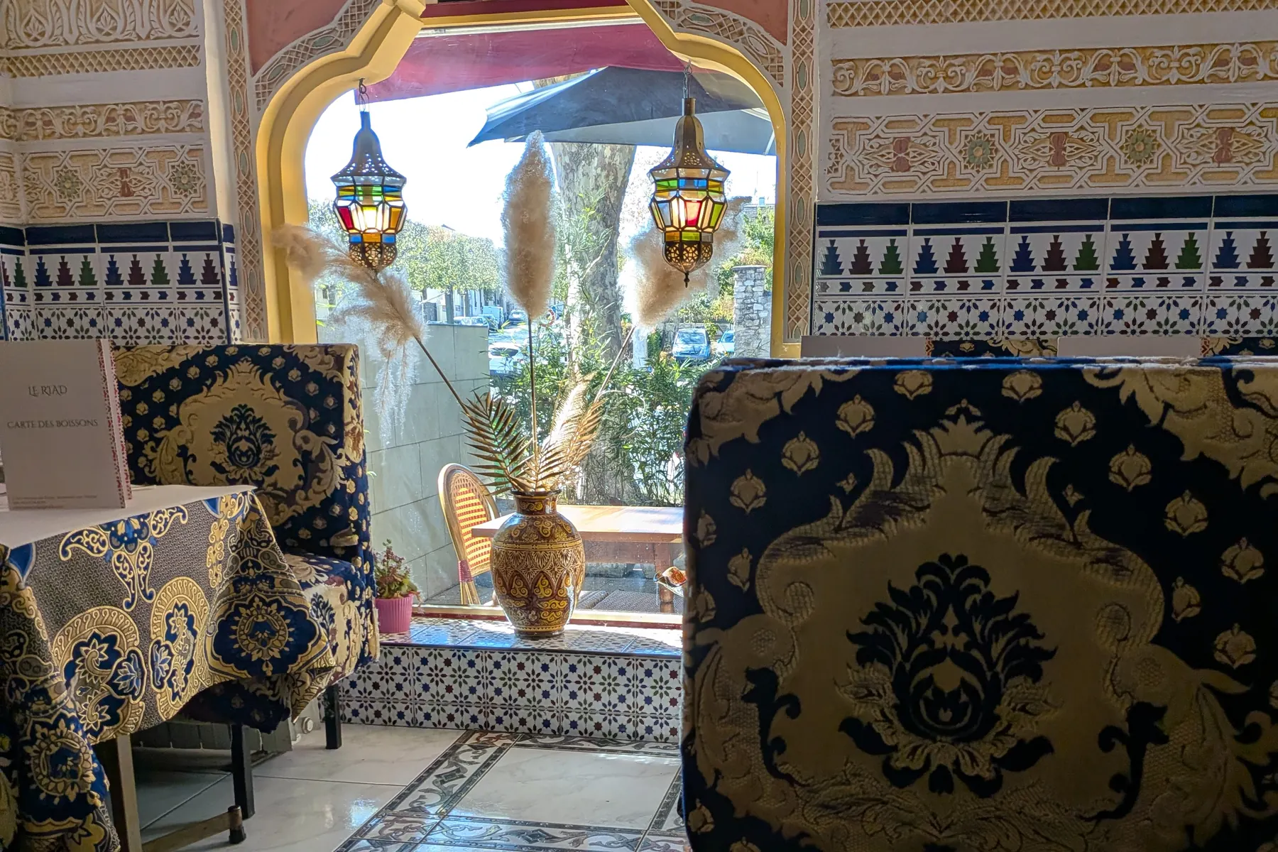 La salle du Riad : arc peint, lanternes et banquettes brodées